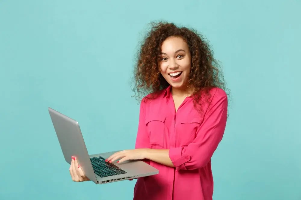 portrait-excited-african-girl-pink-casual-clothes-using-laptop-pc-computer-isolated-blue-turquoise-wall-background-studio-people-sincere-emotions-lifestyle-concept-mock-up-copy-space
